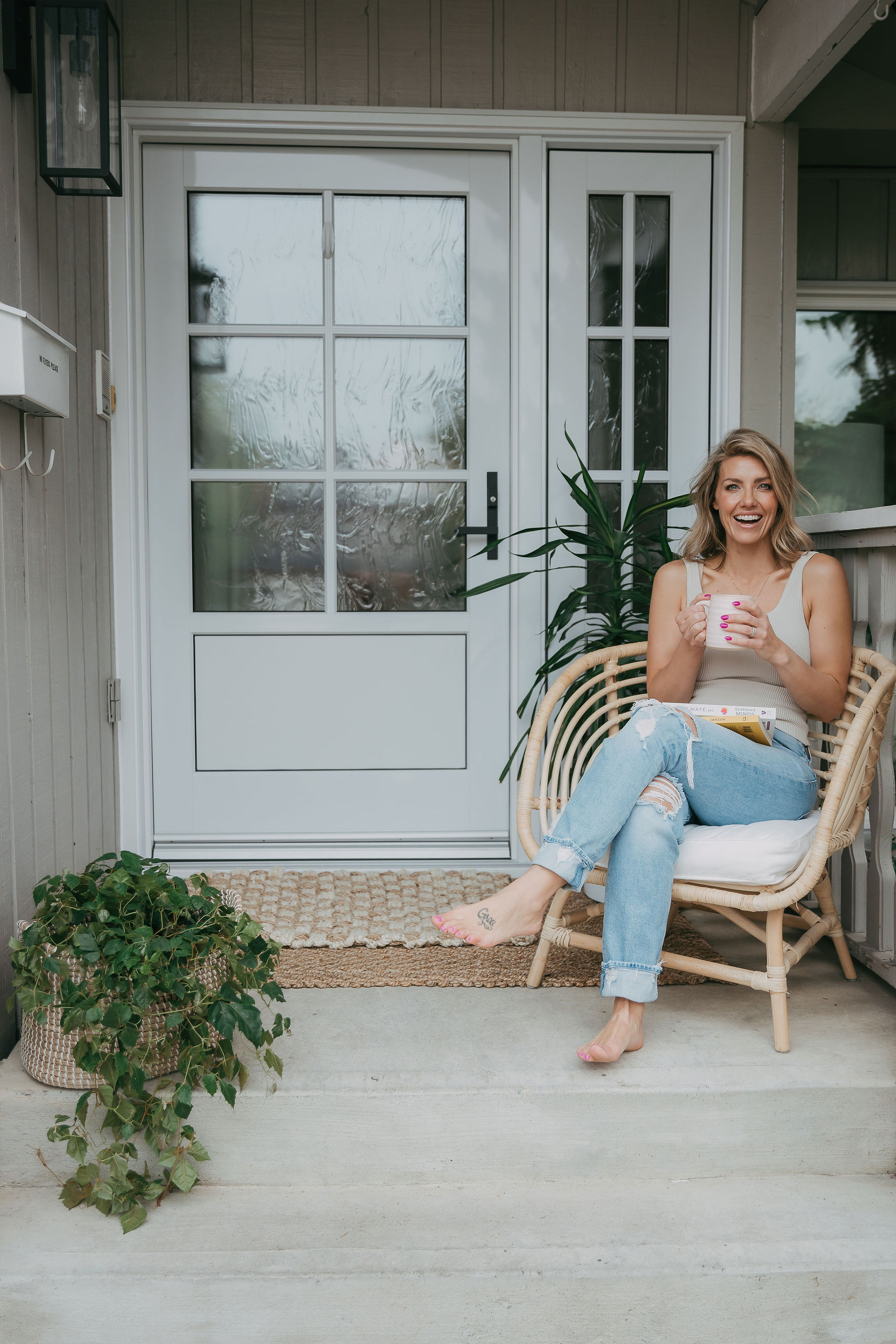 Boho style chair on front porch with Jessica Janzen drinking coffee and fern plant behind her